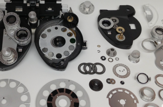 A phoropter fully disassembled, with every lens, disc, and component laid out for cleaning